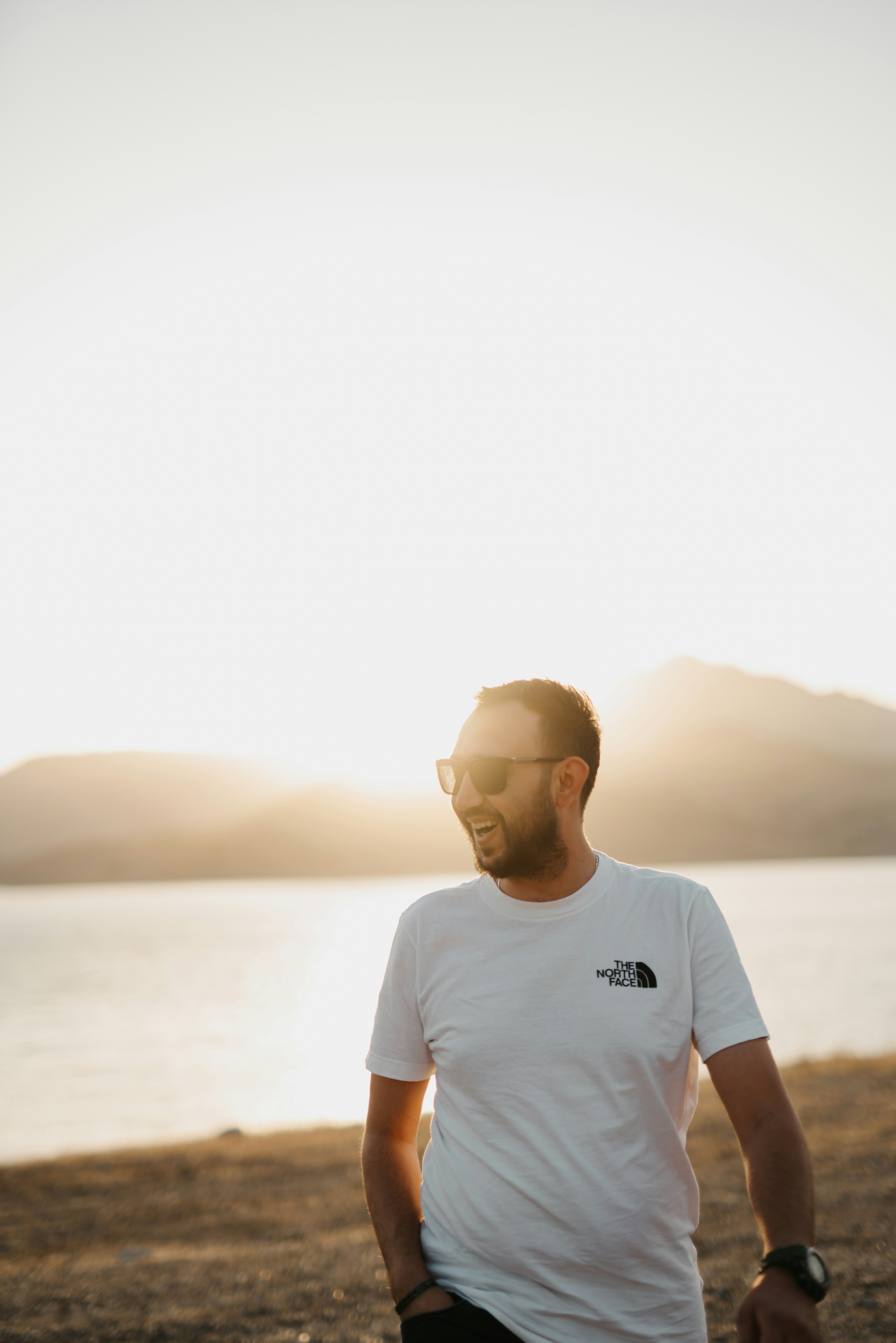 man in white crew neck t-shirt standing near body of water during daytime